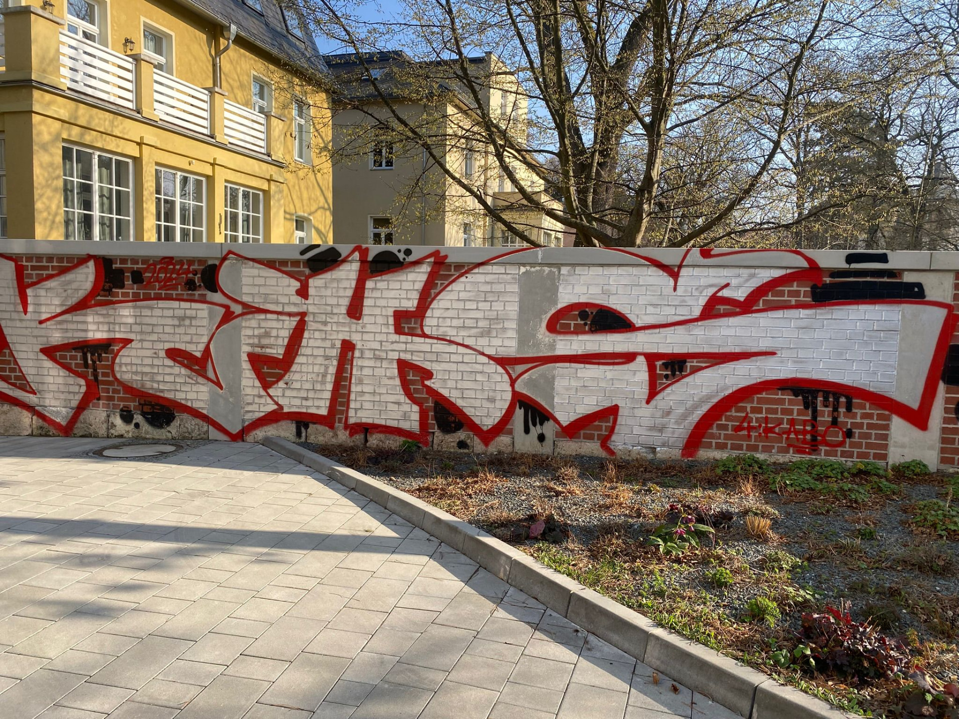 Grundstücksmauer mit rotem Graffiti vor der Graffitientfernung