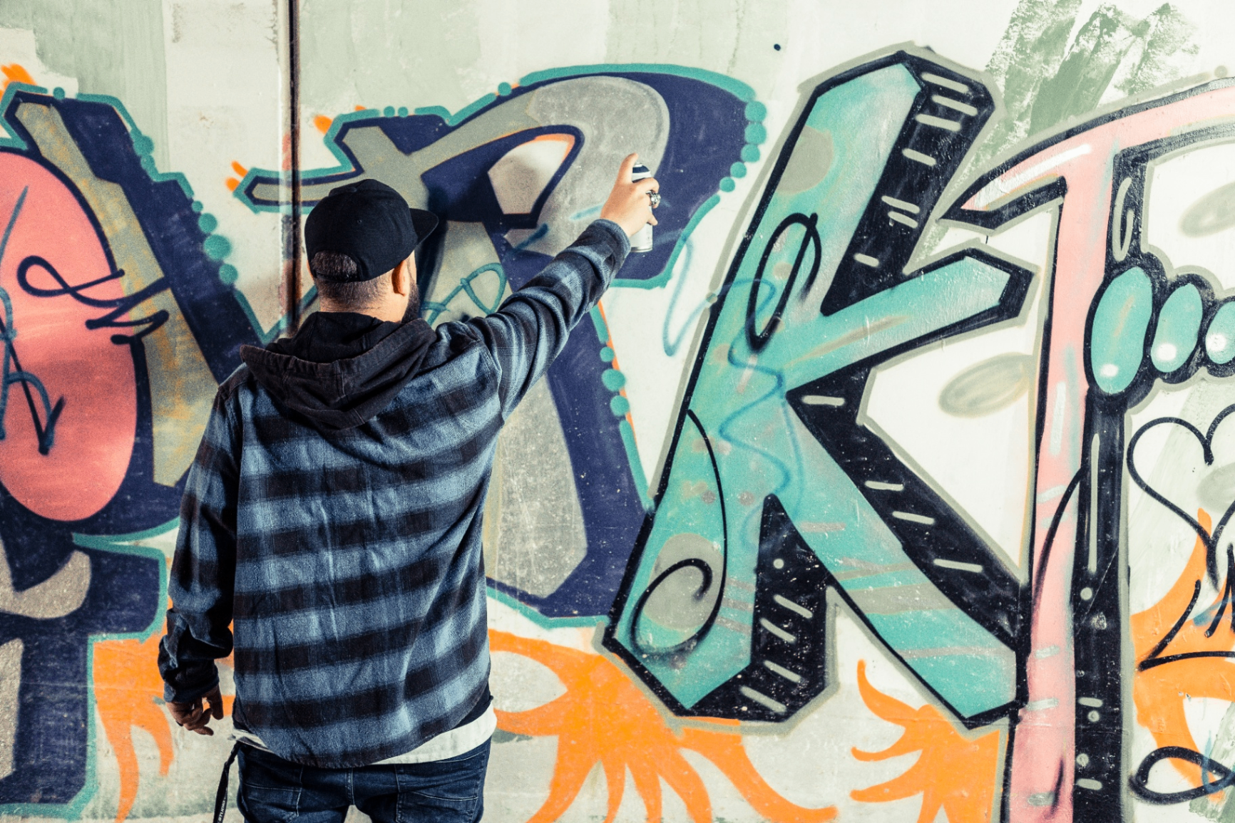 Sprayer besprüht eine Wand mit einem bunten Graffiti